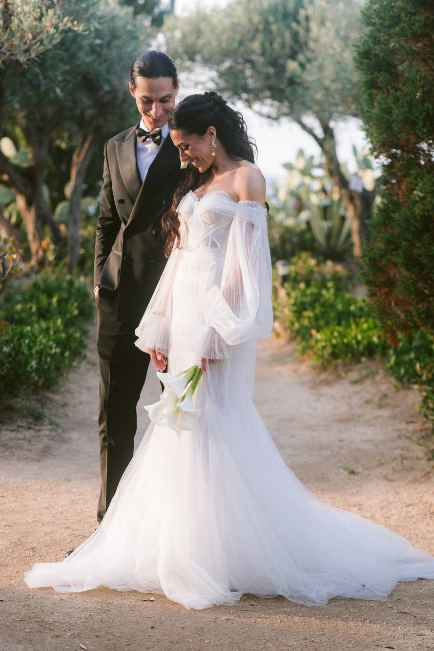 Marianna e Andrea camminano su un sentiero tra ulivi e ficodindia, lei guarda il bouquet di calle, lui la guarda con tenerezza
